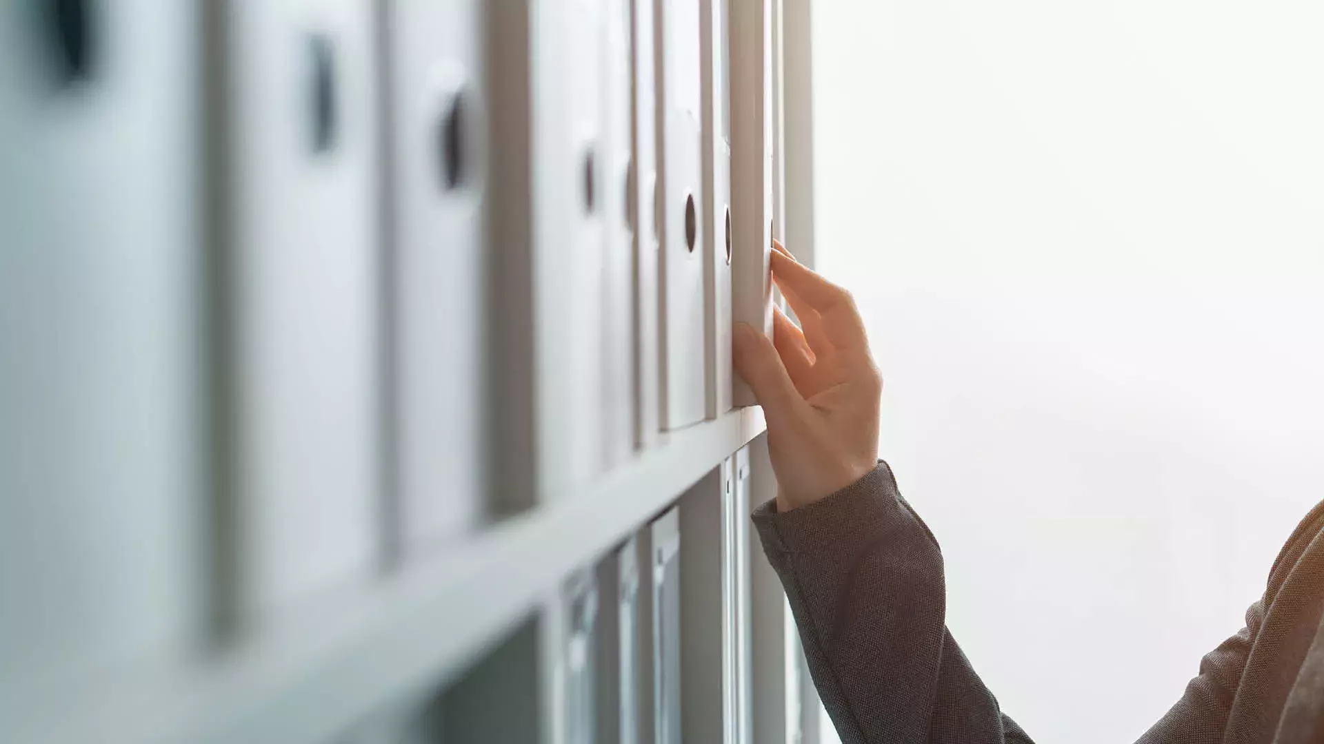 mano appoggiata a scaffale con faldoni di documenti