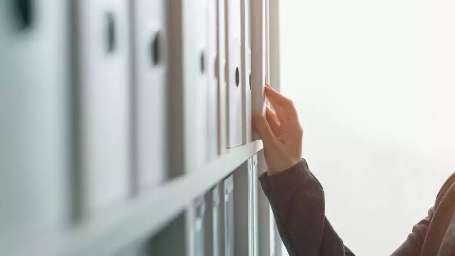 mano appoggiata a scaffale con faldoni di documenti